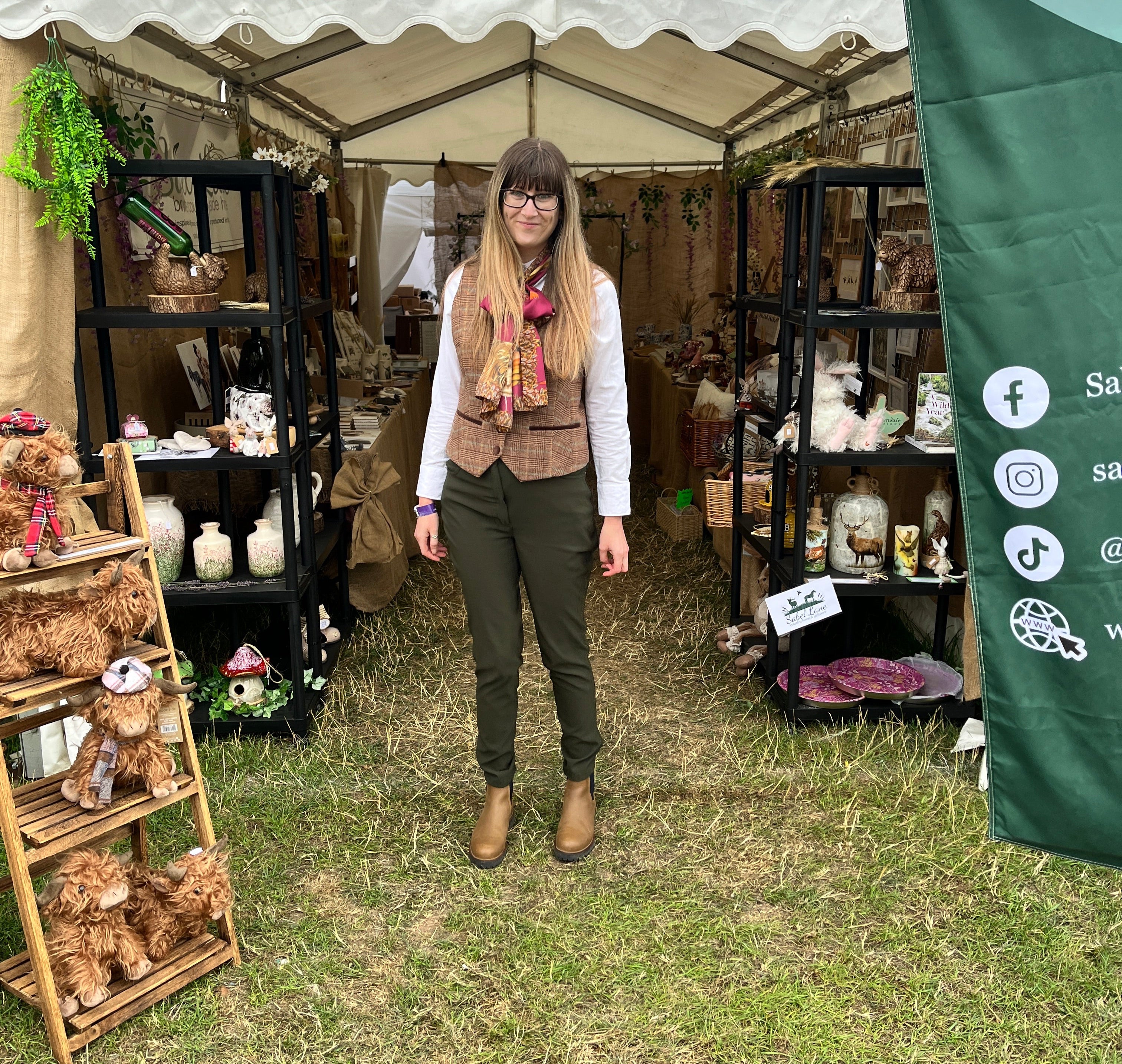 Owner of the business standing in front of her market stall with various items on display.