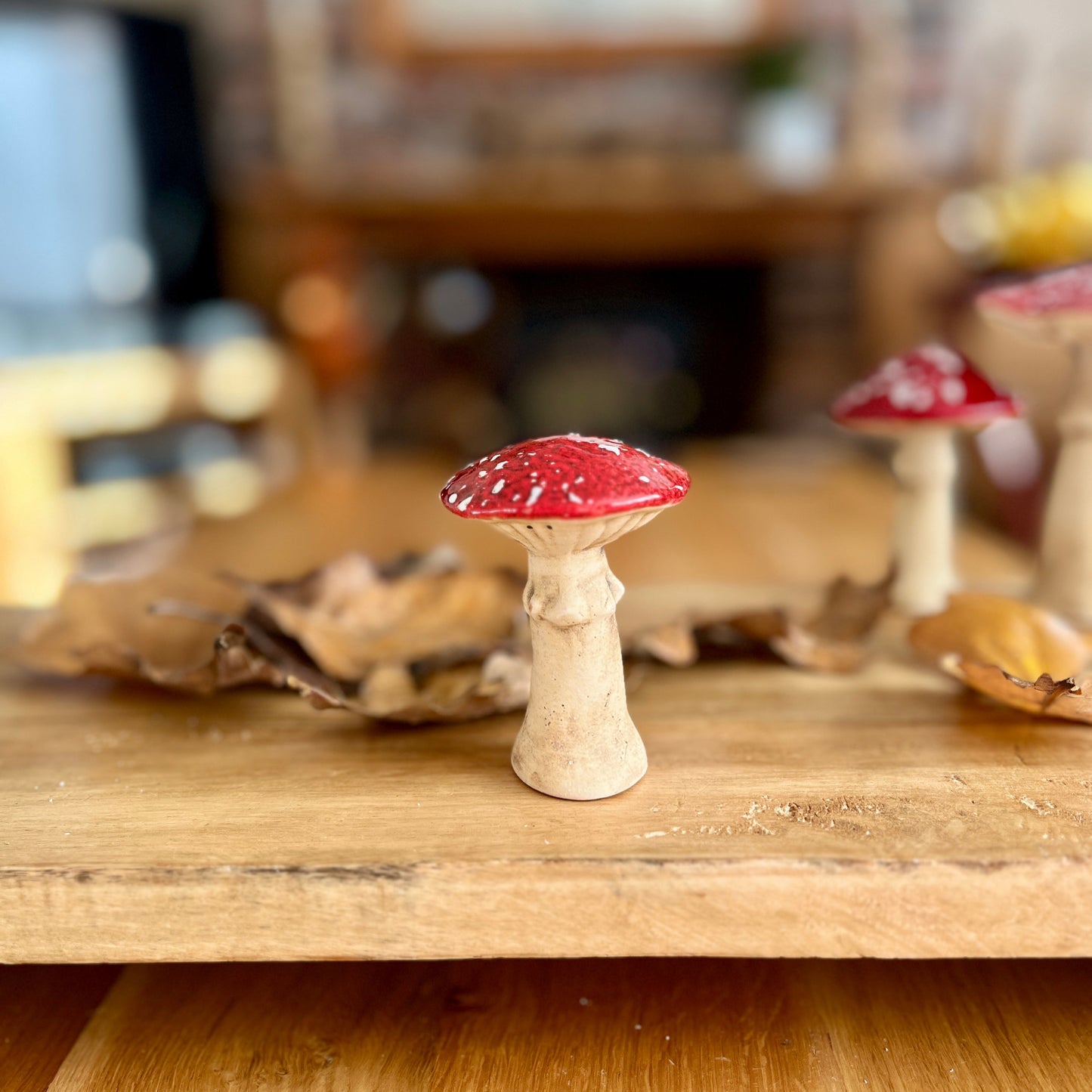 Small decorative mushroom with a red cap on a wooden surface.