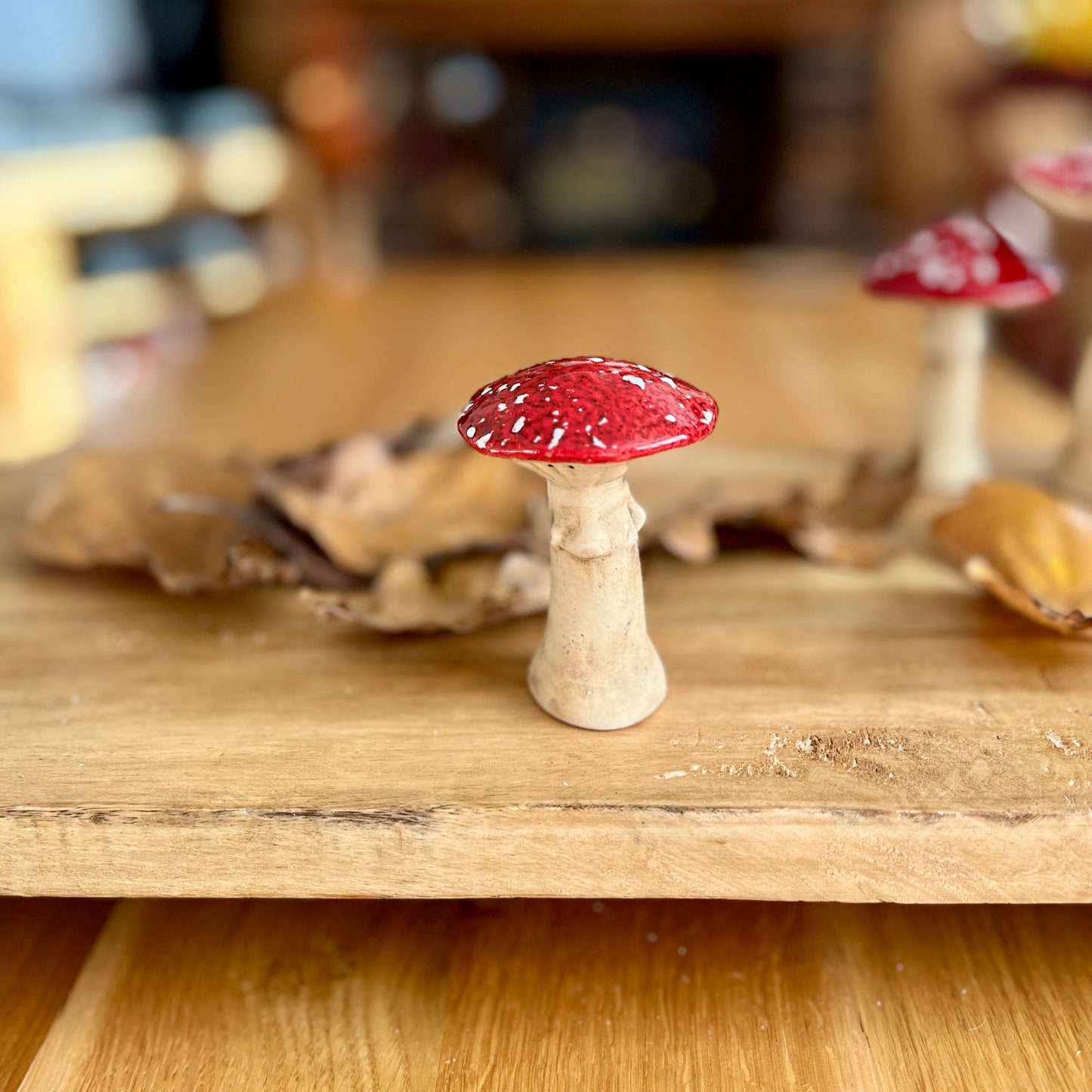 Small figurine of a red and white mushroom on a wooden surface with a blurred background