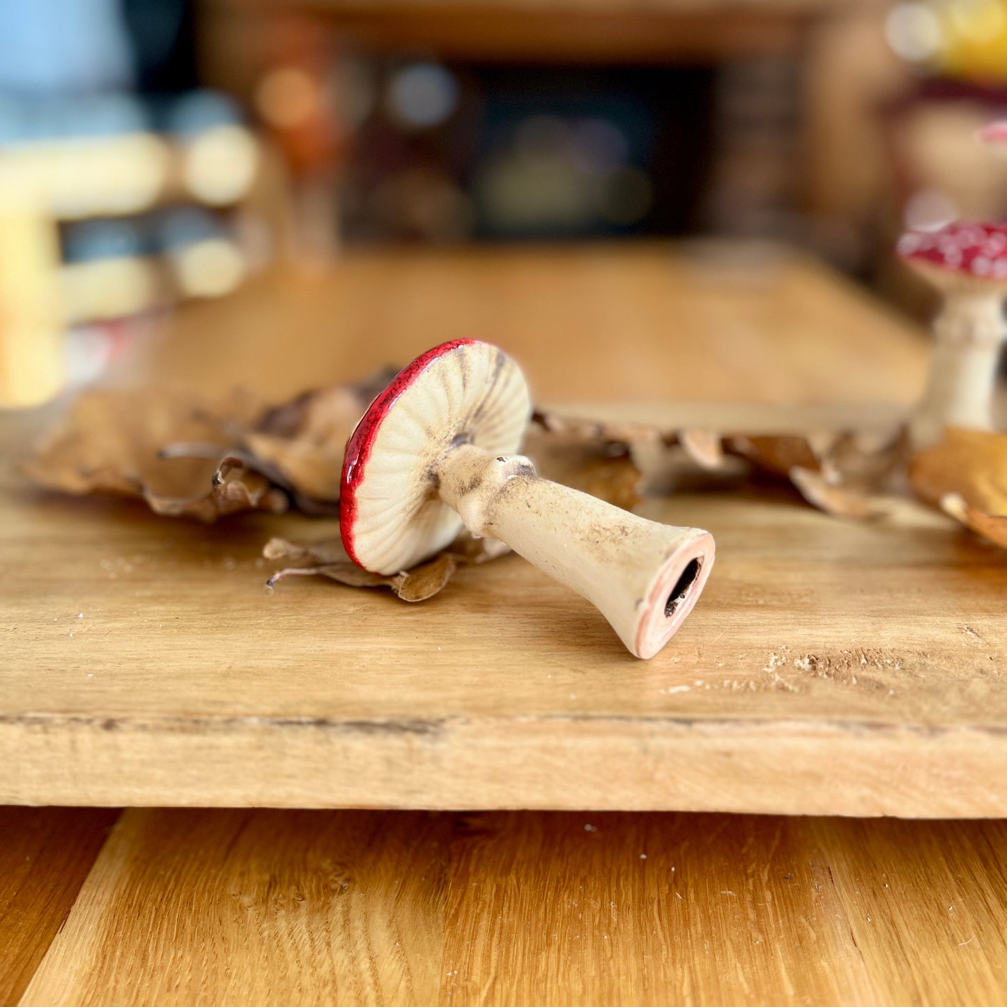 Ceramic figurine of a mushroom on its side on a wooden surface with a blurred background
