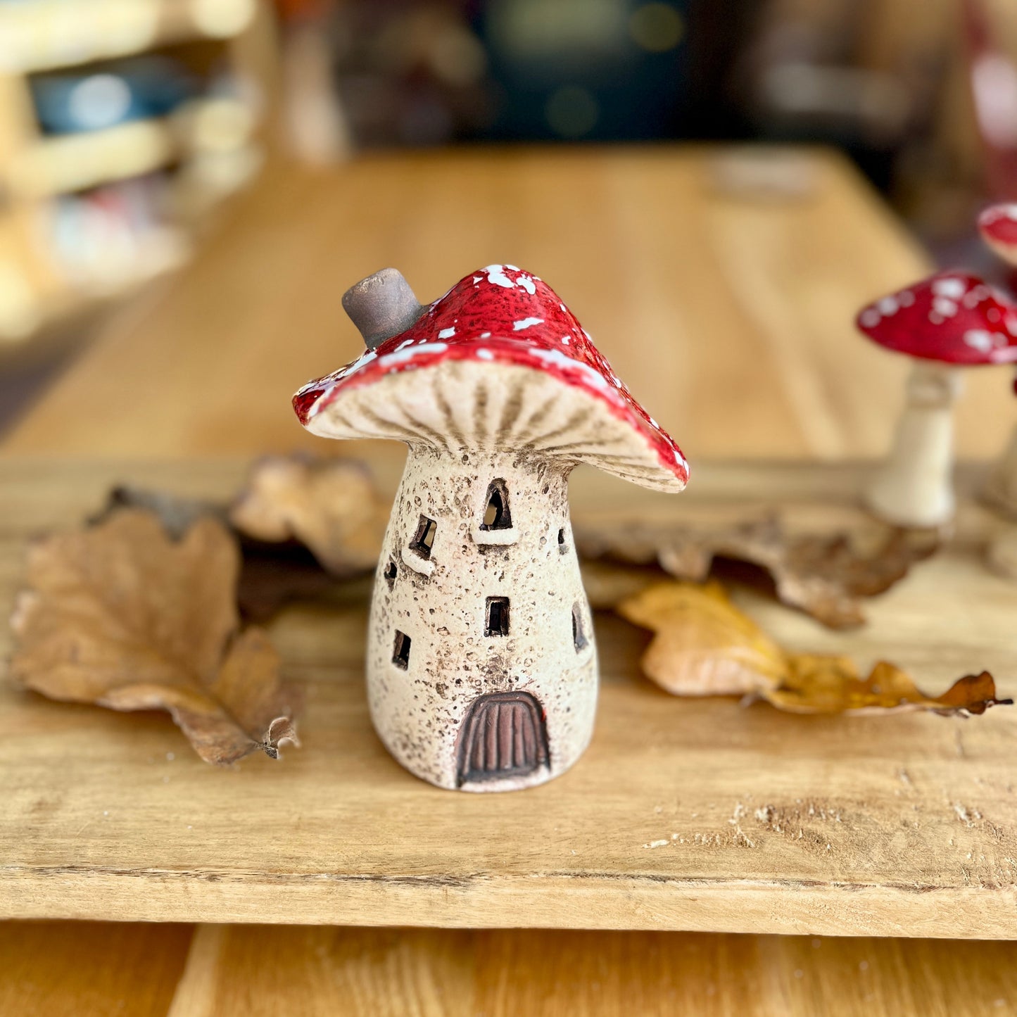 Small ceramic mushroom with red cap on a wooden surface
