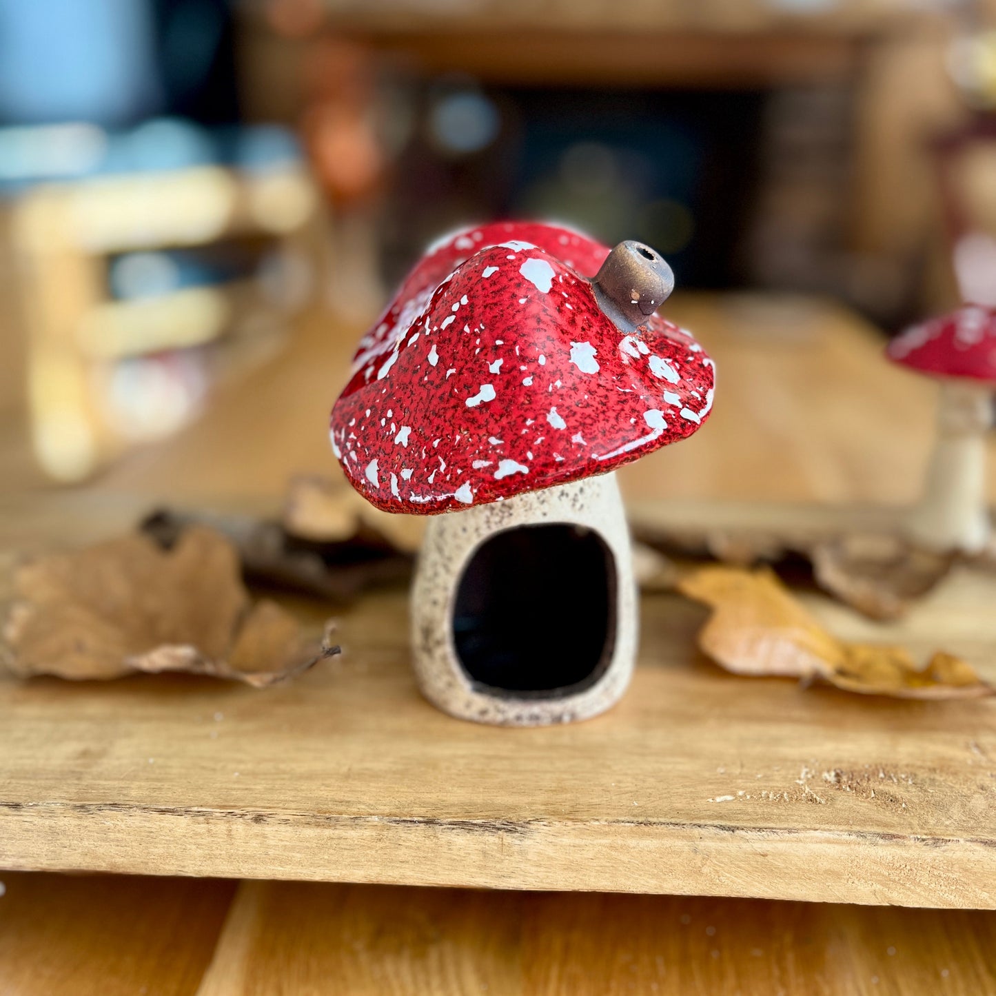 Small mushroom shaped house with gap for candle on a wooden surface with blurred background