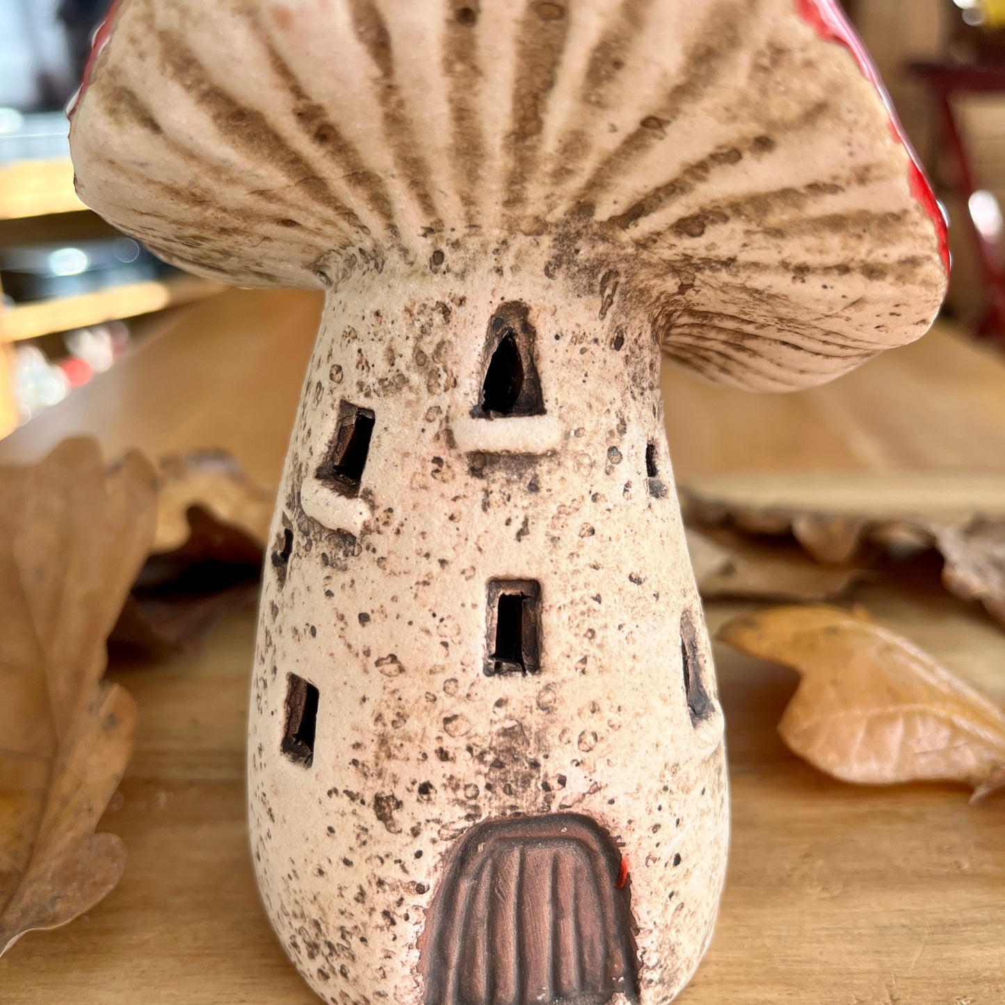 close up of a ceramic mushroom shaped house on a wooden surface with blurred background