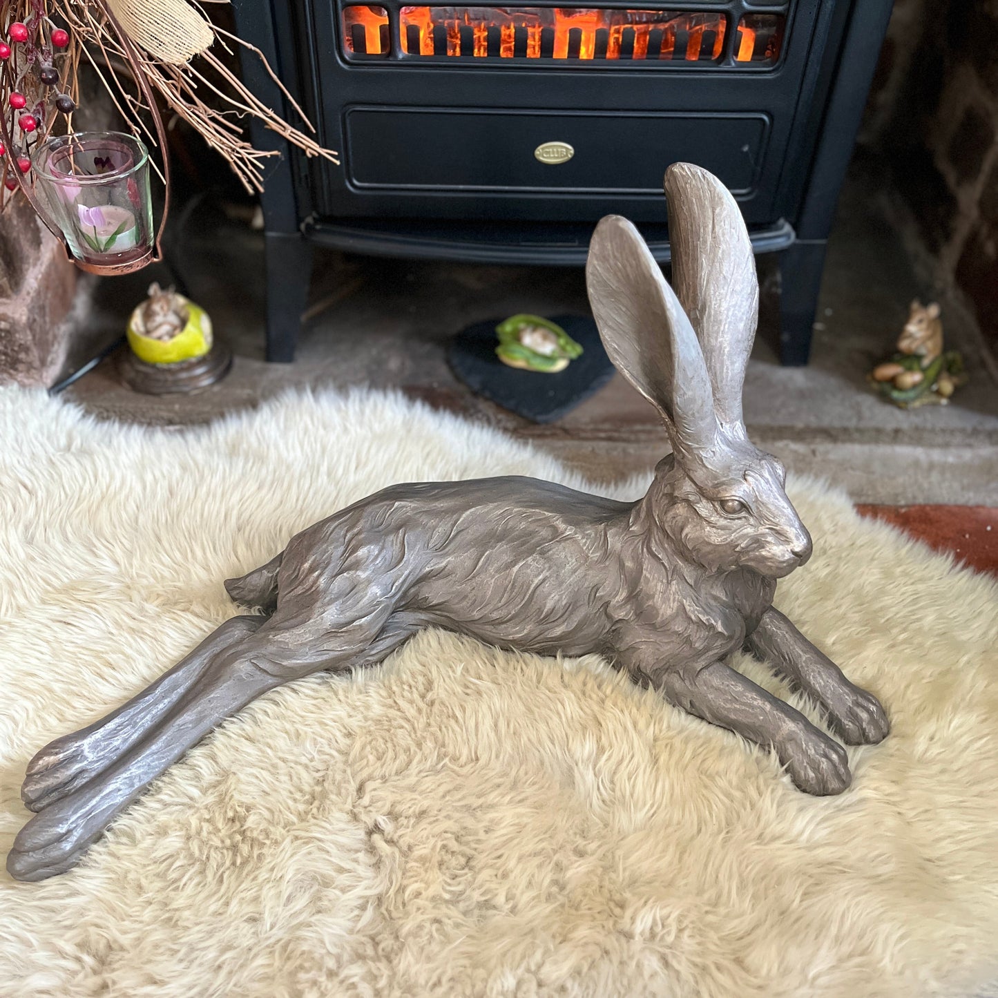 Ornamental hare from above lay on a sheepskin rug in front of an electric fire