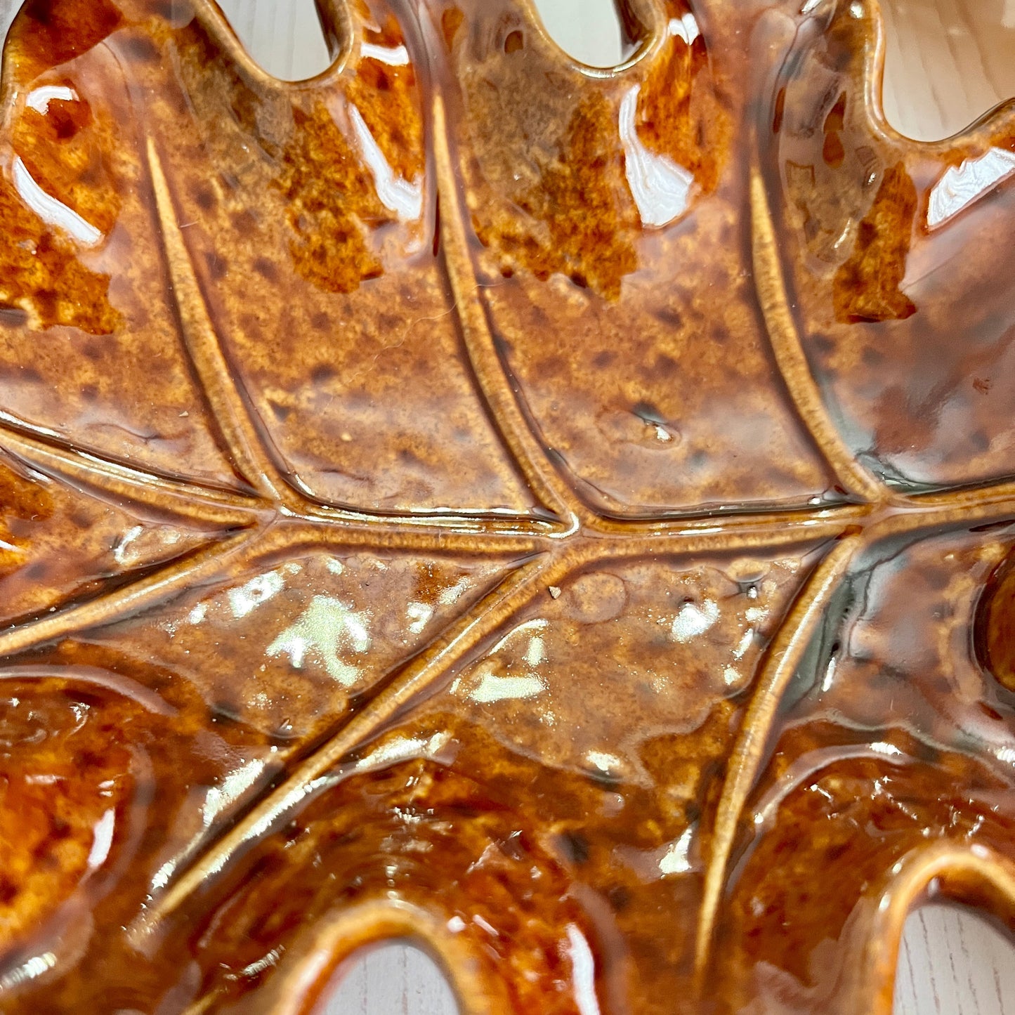 Close-up of the middle of a brown ceramic leaf-shaped object on a white background