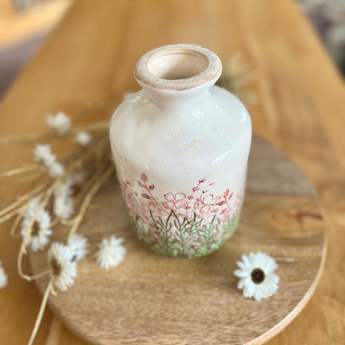 Small decorative bottle vase with floral design on a wooden surface