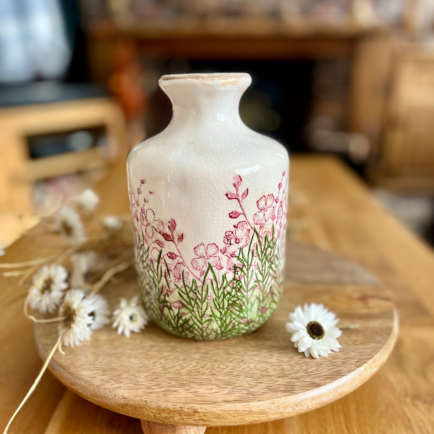 Decorative bottle vase with floral design on a wooden stand