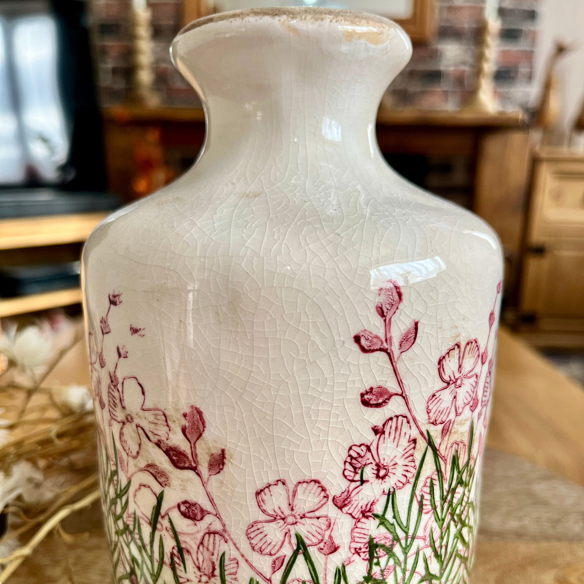 Close up of decorative vase highlighting the crackle effect with floral design on a wooden surface