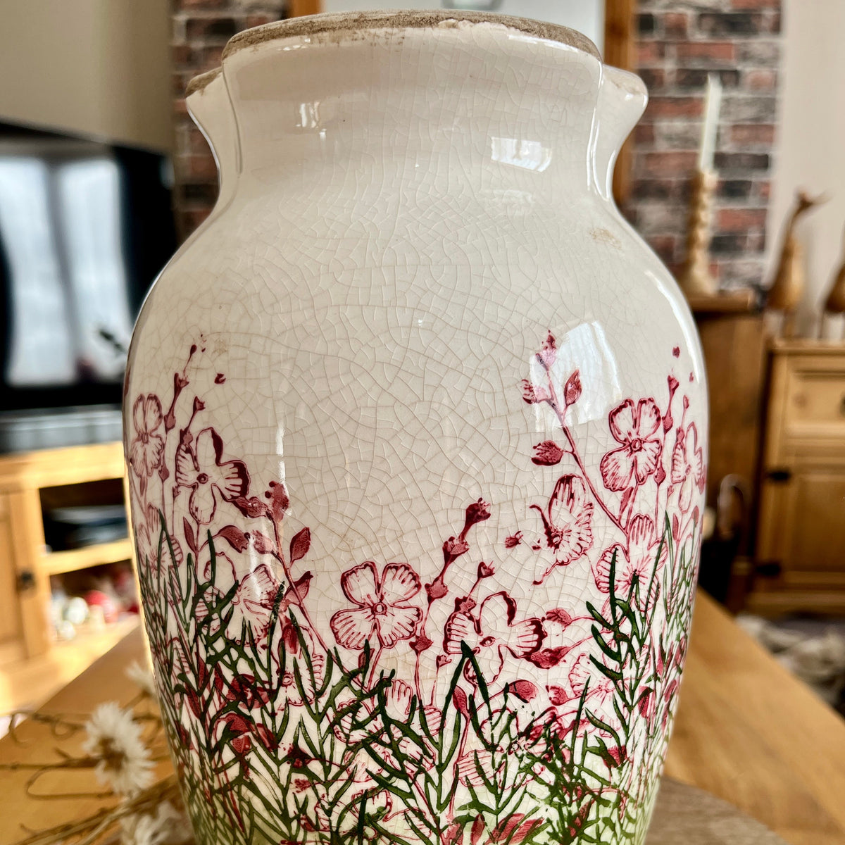 Close up of decorative vase with floral design highlighting crackle effect on a wooden surface