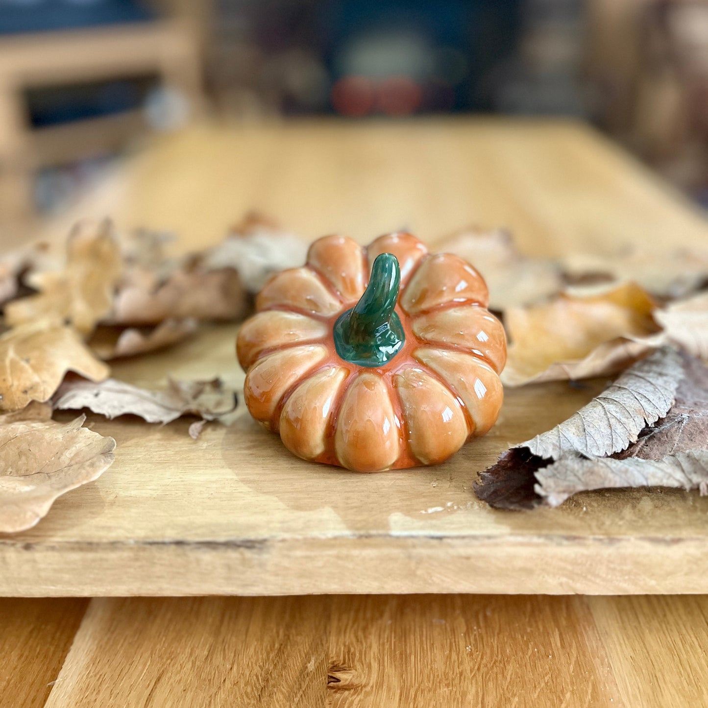 Small ceramic pumpkin on a wooden surface with blurred background