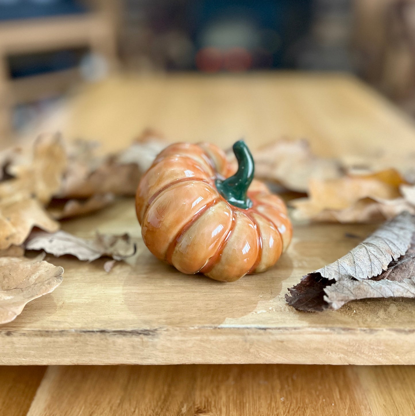 Small pumpkin decoration on a wooden surface with dried leaves
