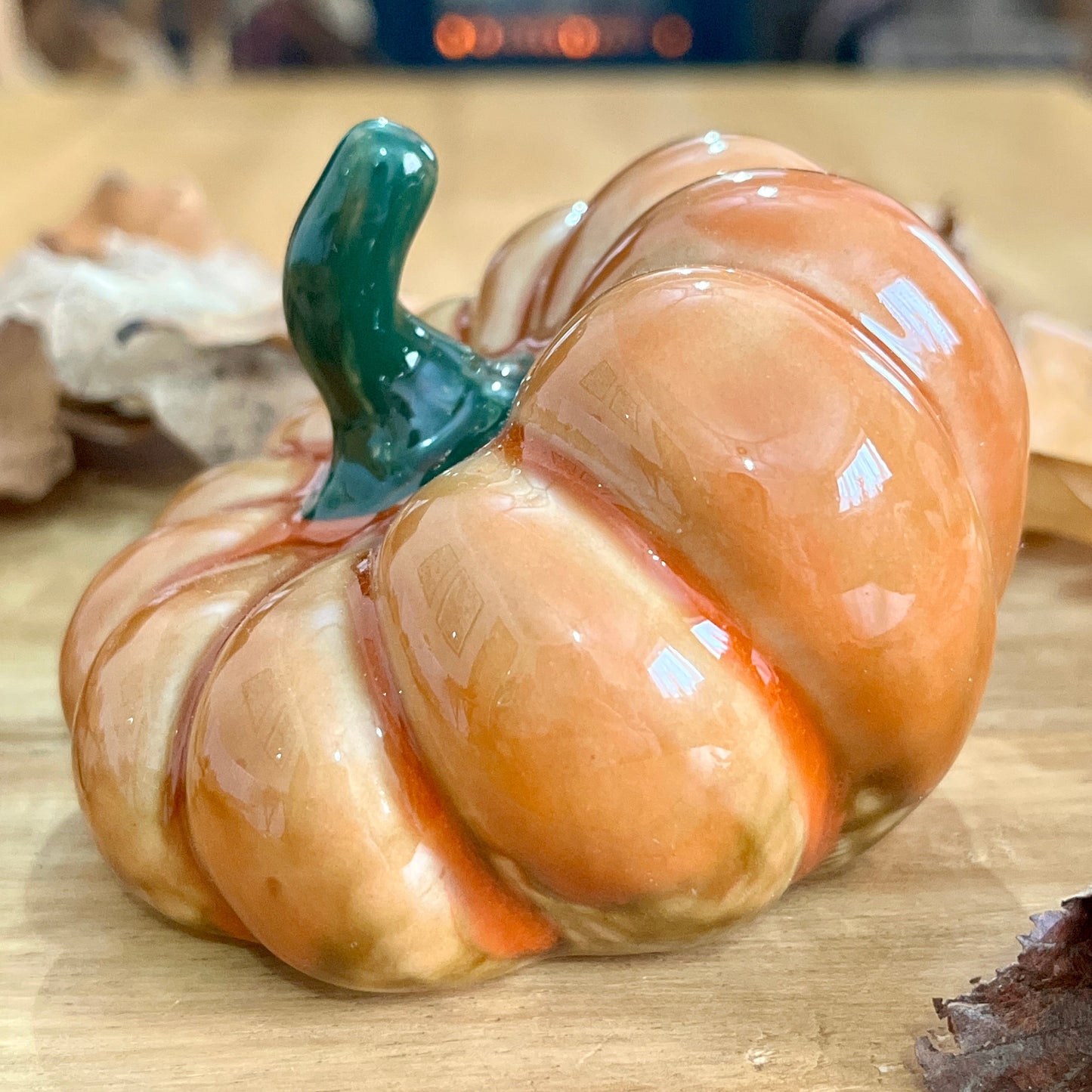Close up of decorative pumpkin with a green stem on a wooden surface