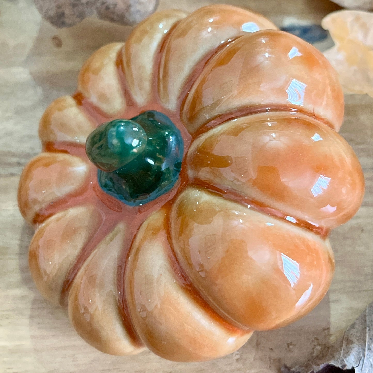 Close up of decorative pumpkin from above with a green centre on a textured beige background