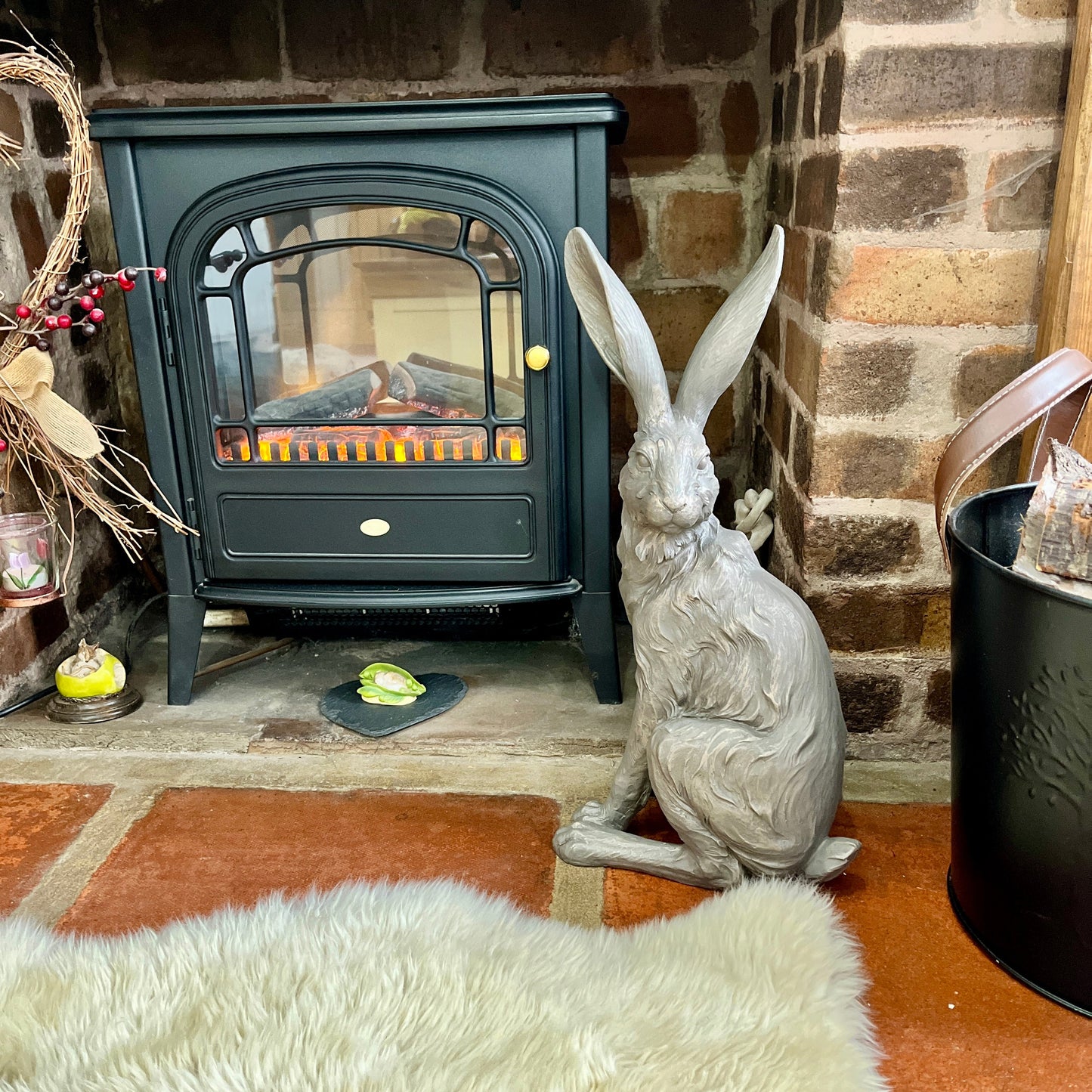 Decorative hare figure in front of a lit fireplace with a brick wall background.
