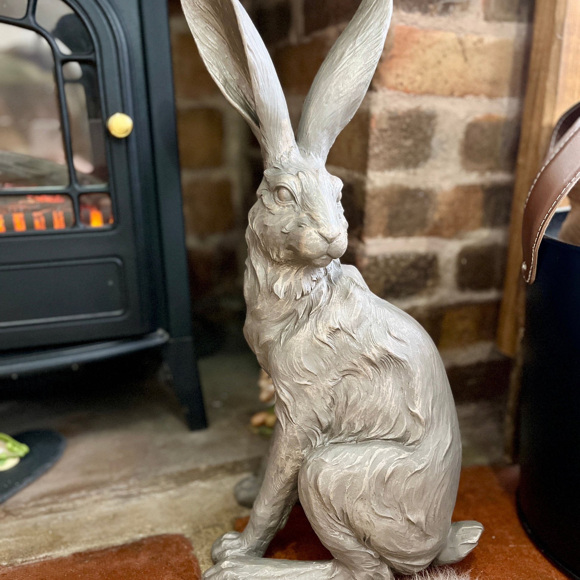 Statue of a hare in front of a fireplace with a brick wall background