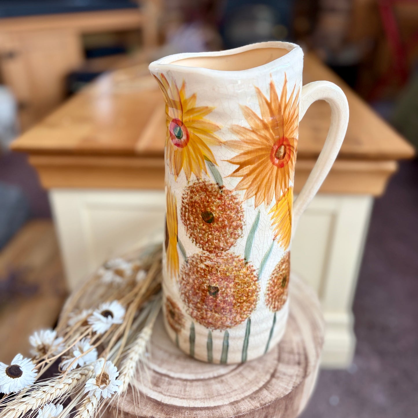 Decorative jug with sunflower design on a wooden stool