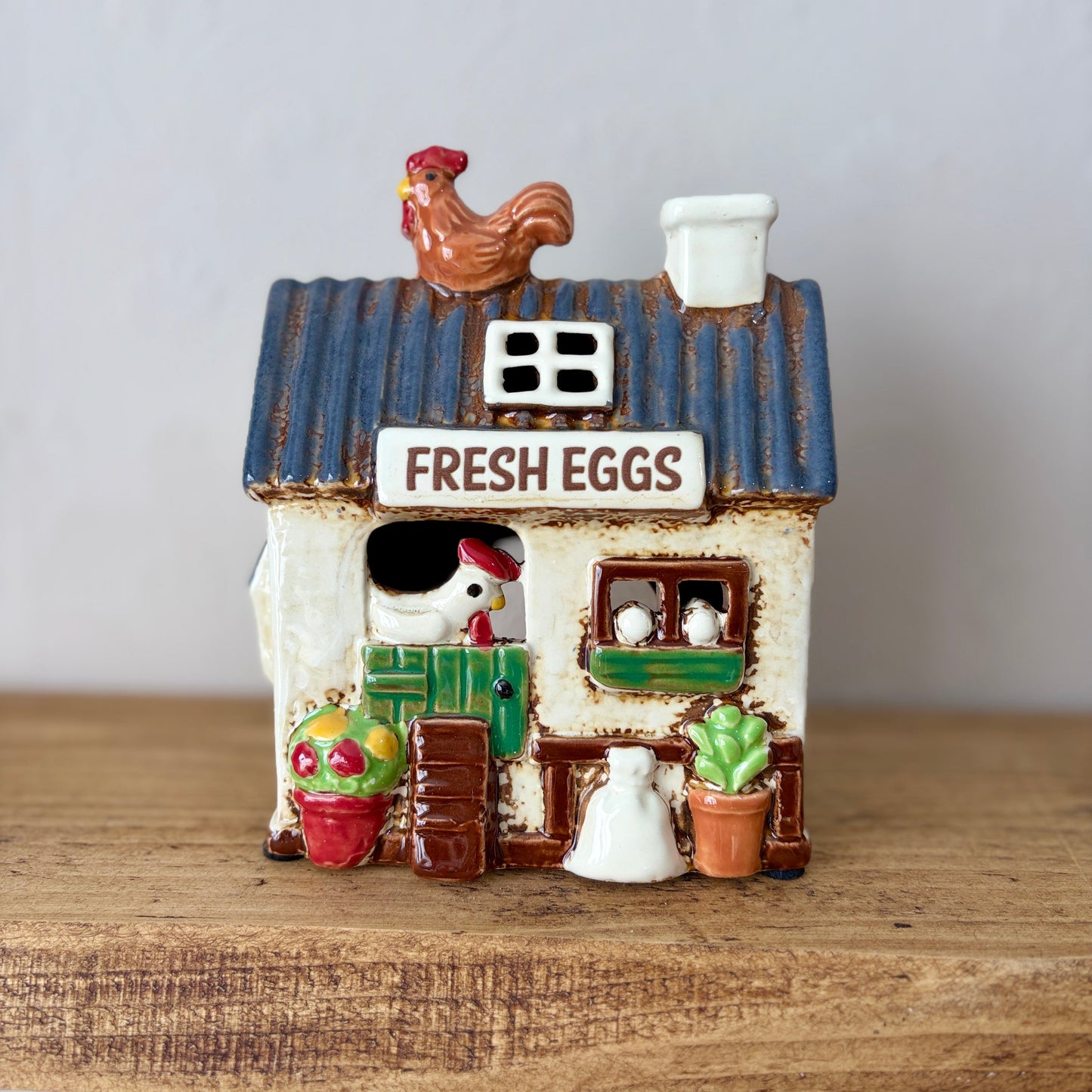 Decorative candle holder chicken coop with rooster on top, featuring 'Fresh Eggs' text, on a wooden surface.