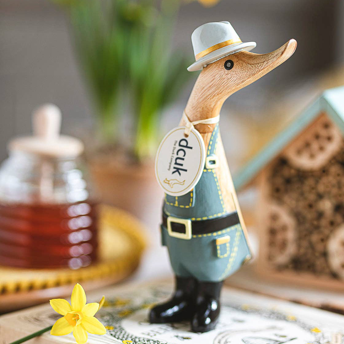 Wooden duck figurine in a hat on a book with flowers and honeycomb in the background