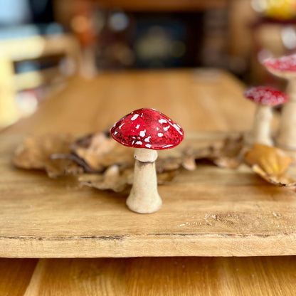 Decorative red and white mushroom on a wooden surface with a blurred background