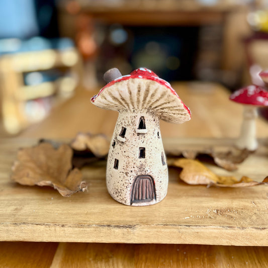 Small mushroom shaped house figurine on a wooden surface with blurred background