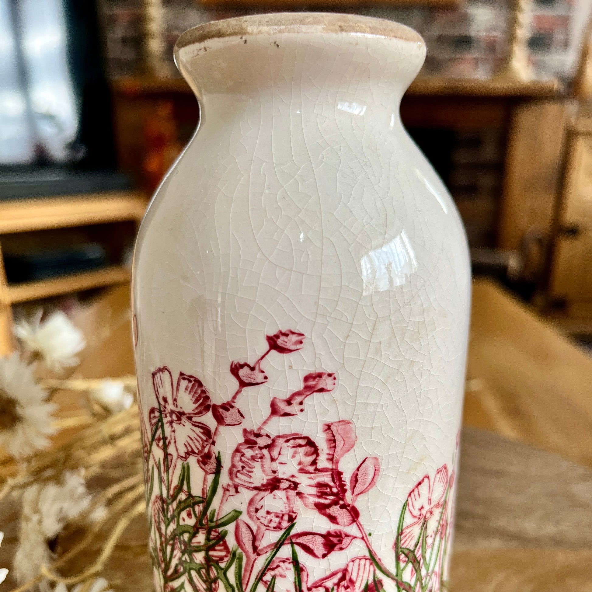 White ceramic bottle shaped vase with floral design highlighting the crackle effect on a wooden surface