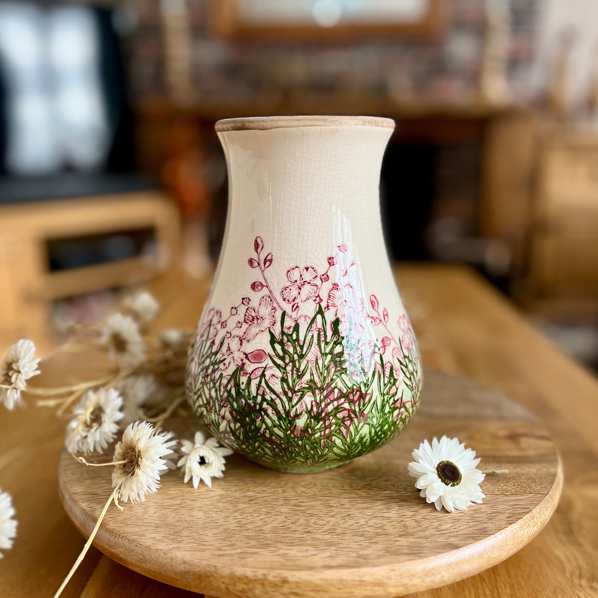 Decorative vase with floral design on a wooden stand in a home setting