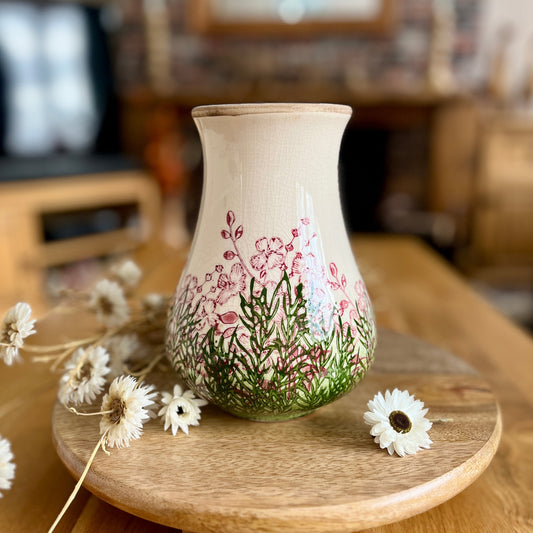 Decorative vase with floral design on a wooden stand in a home setting