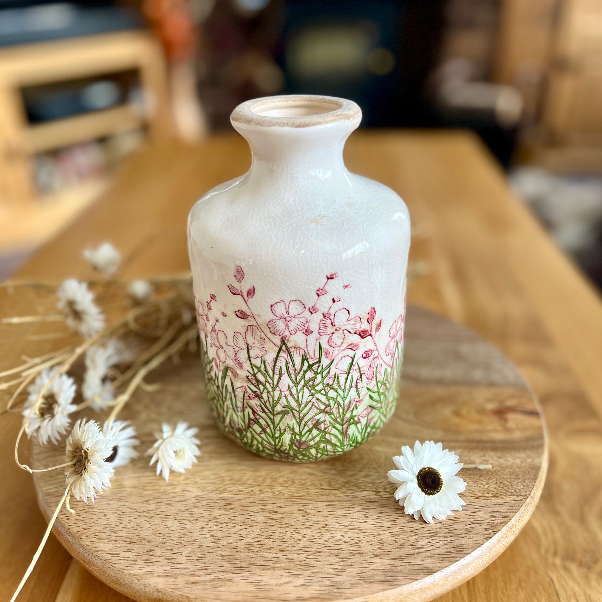Decorative bottle vase with floral design on a wooden surface