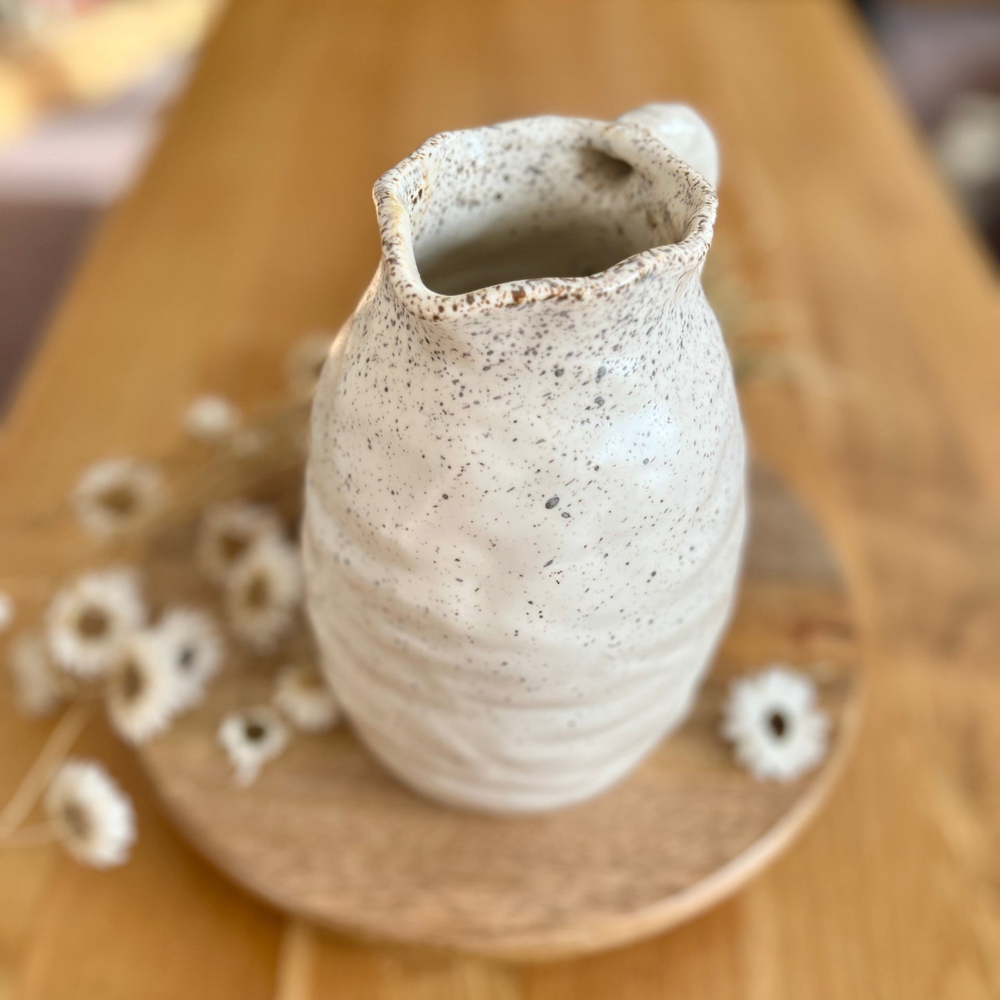 Speckled ceramic vase on a wooden surface with blurred background