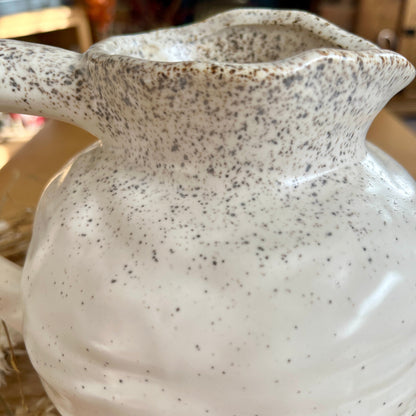 Close up of speckled ceramic jug on a wooden surface