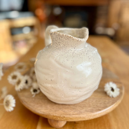 Small ceramic vase on a wooden stand with blurred background