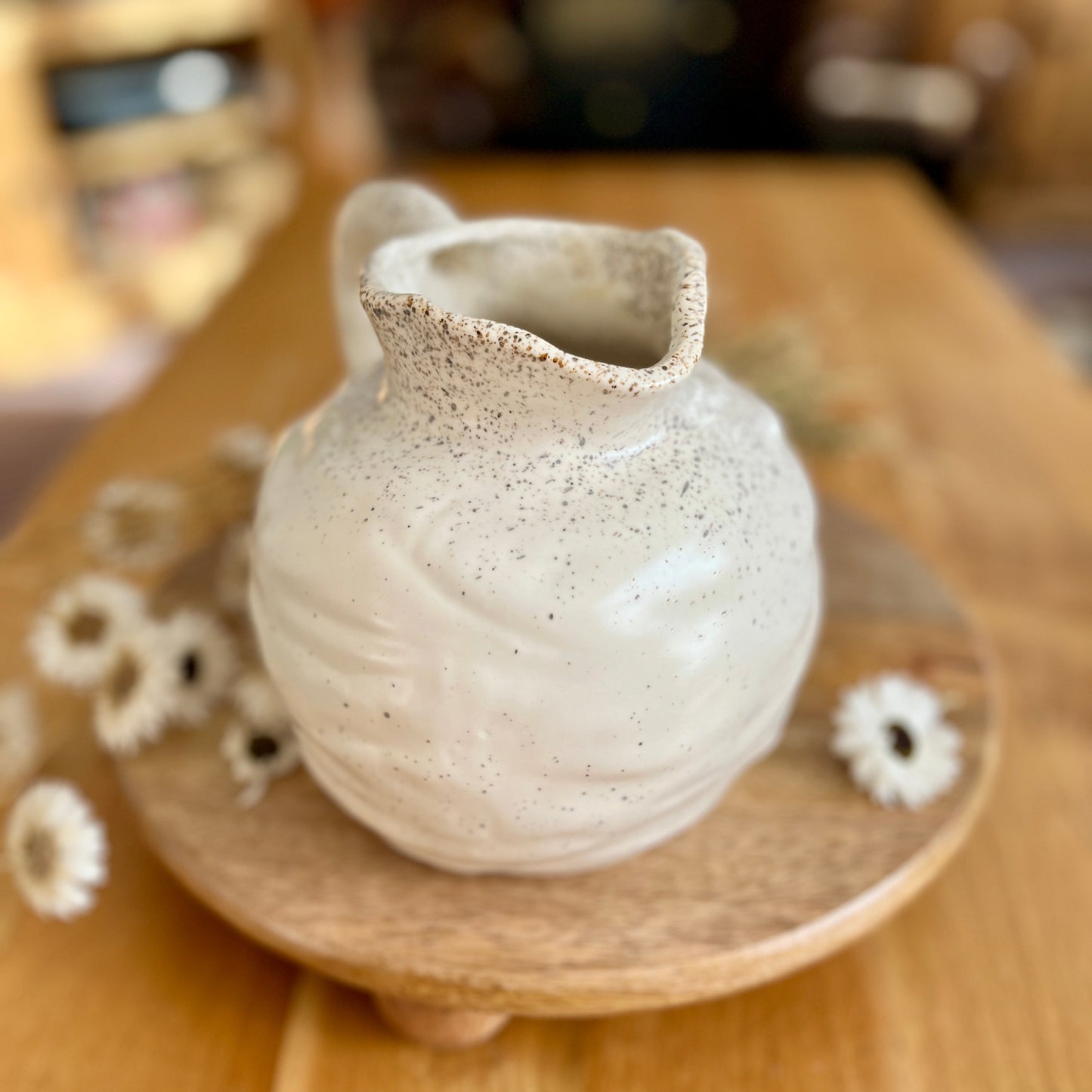 Small ceramic jug on a wooden stand with a blurred background