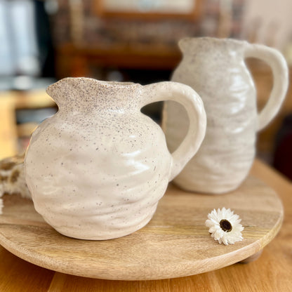 Matching ceramic jugs on a wooden surface with a blurred background