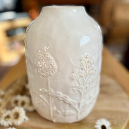 White ceramic vase with floral patterns on a wooden surface
