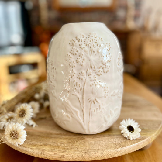 White textured ceramic vase on a wooden tray with dried flowers