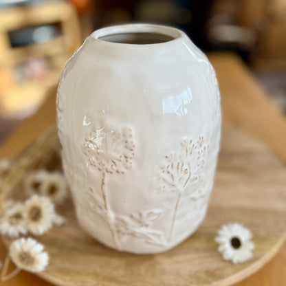 Ceramic vase with floral embossing on a wooden surface
