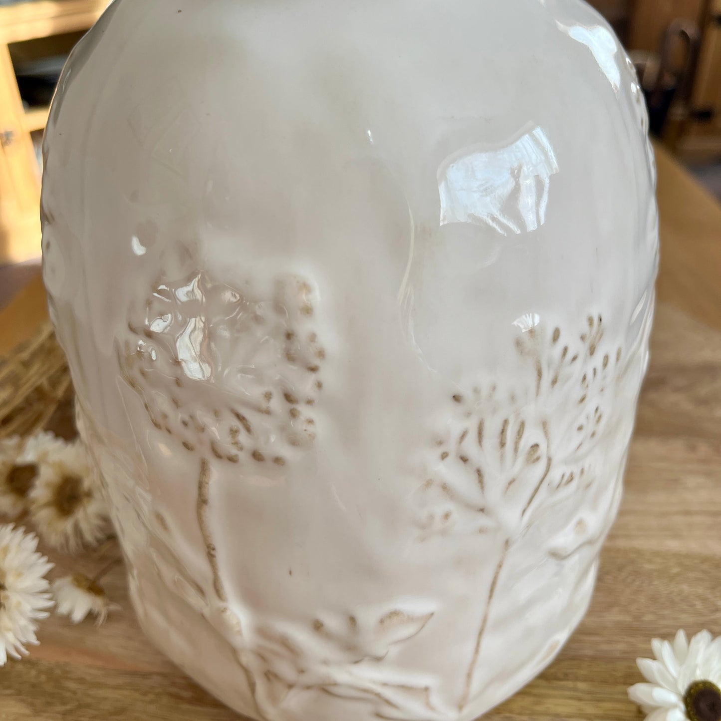 Close up white ceramic vase with embossed design on a wooden surface