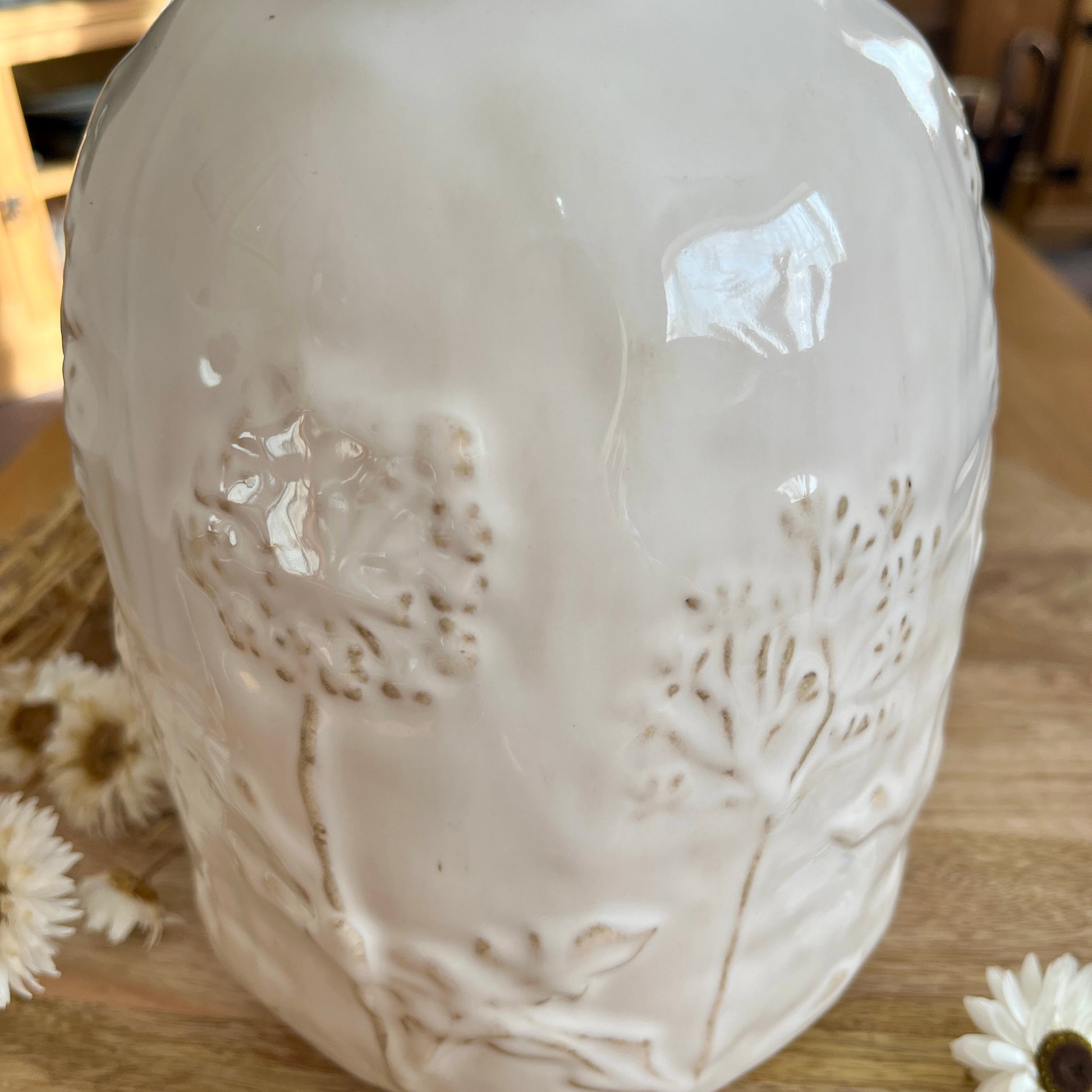 Close up white ceramic vase with embossed design on a wooden surface