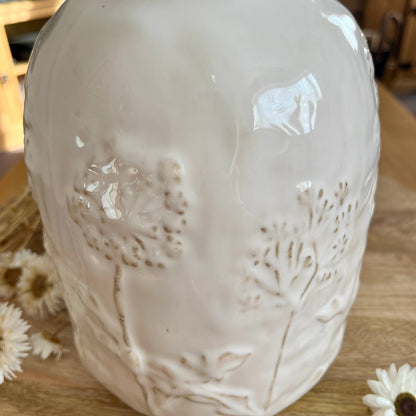 Close up white ceramic vase with embossed design on a wooden surface