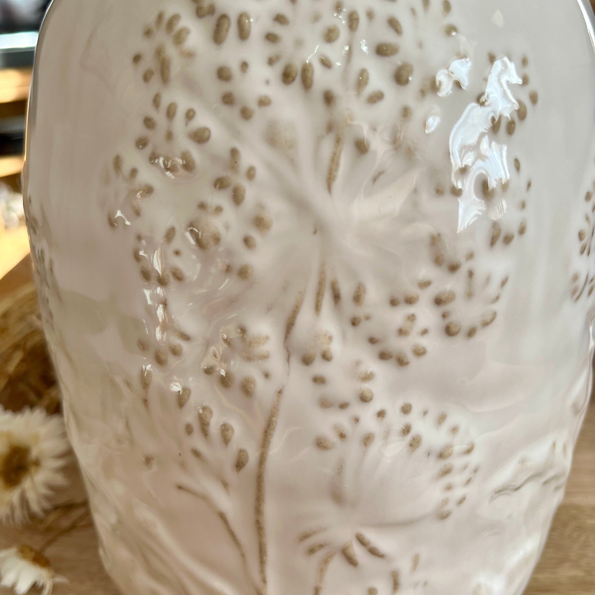 Close up of white ceramic vase with intricate patterns on a wooden surface