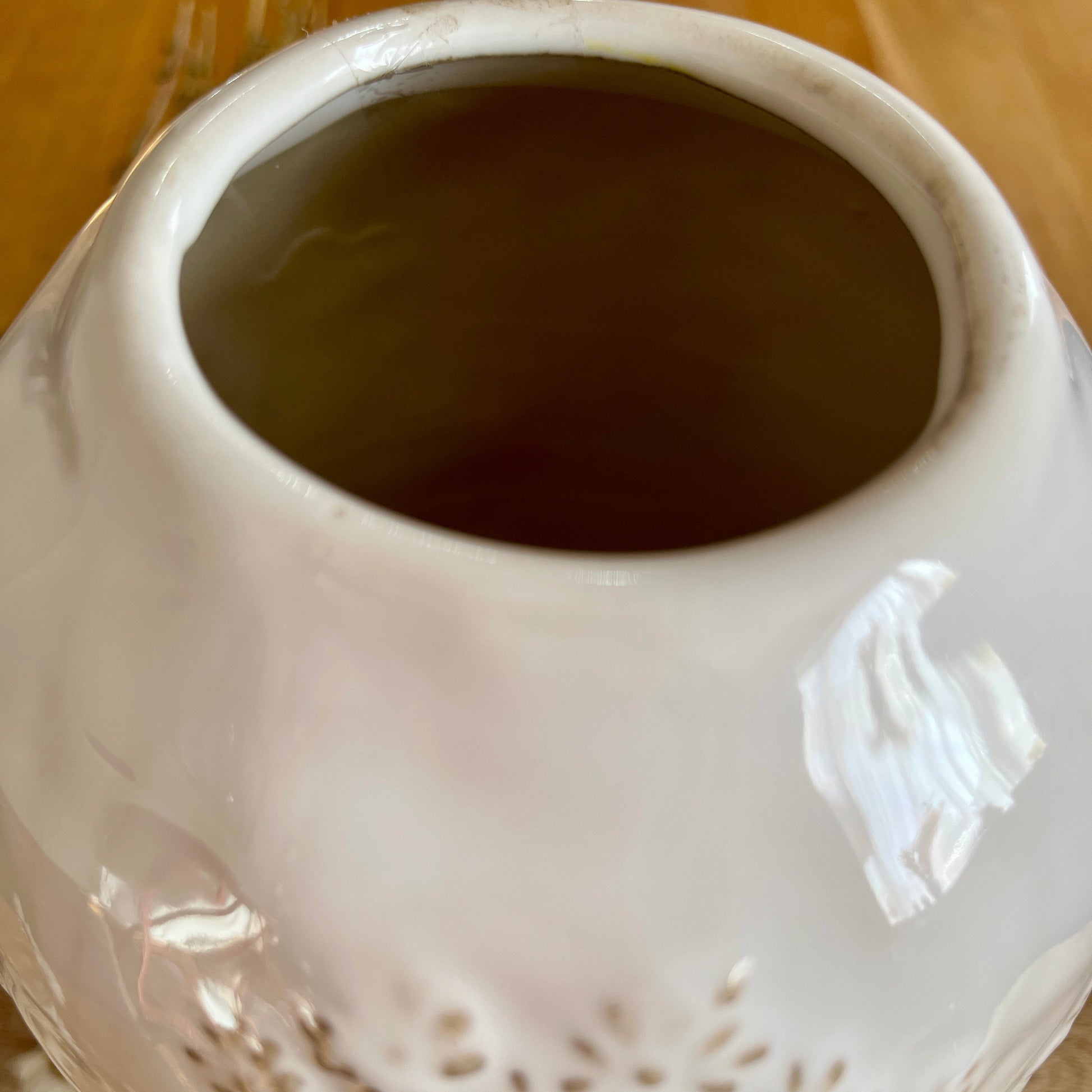 White ceramic vase with textured surface from the top on a wooden surface