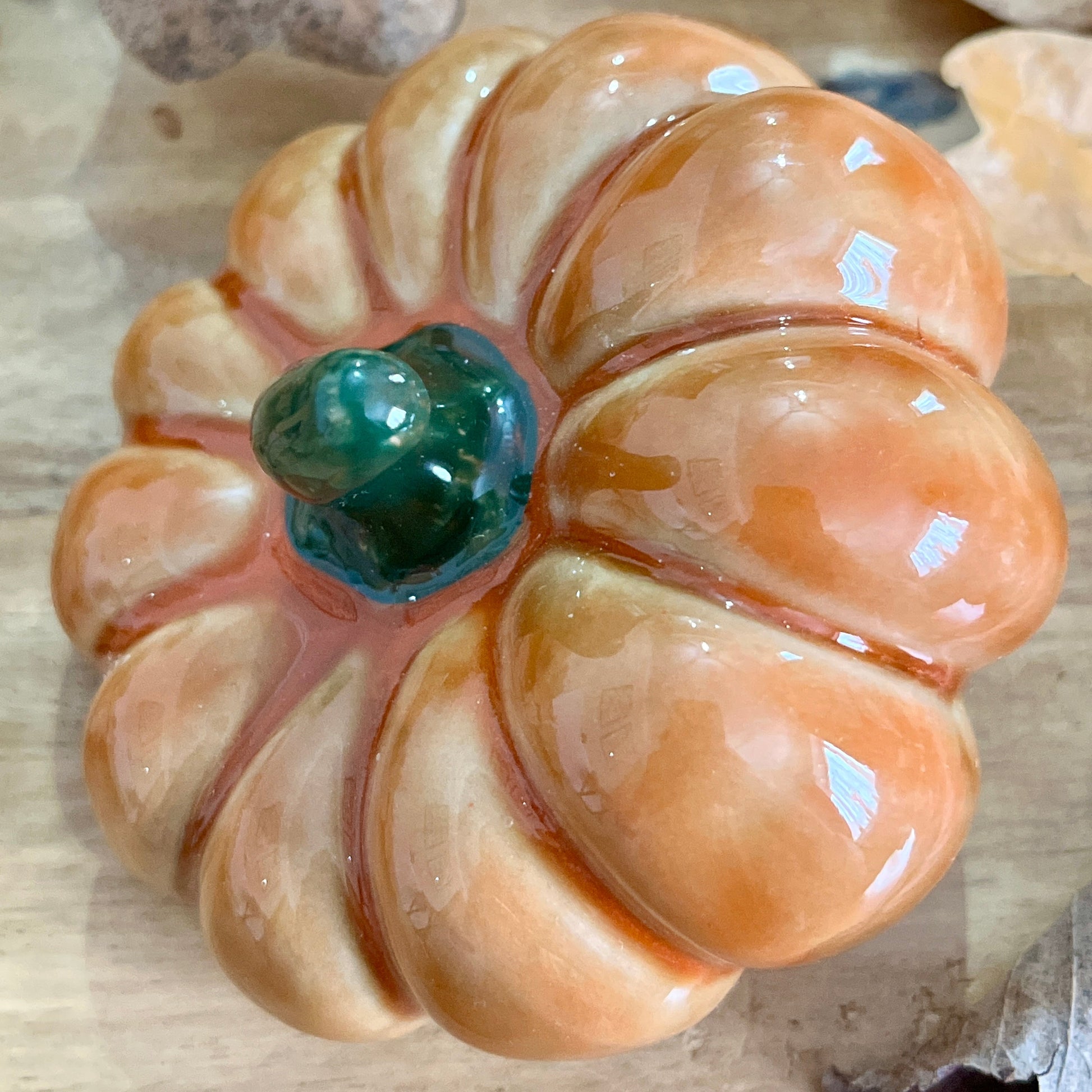 Close up of decorative pumpkin from above with a green centre on a textured beige background