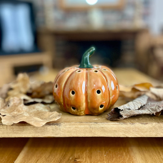 Ceramic pumpkin shaped decoration on a wooden surface with blurred background