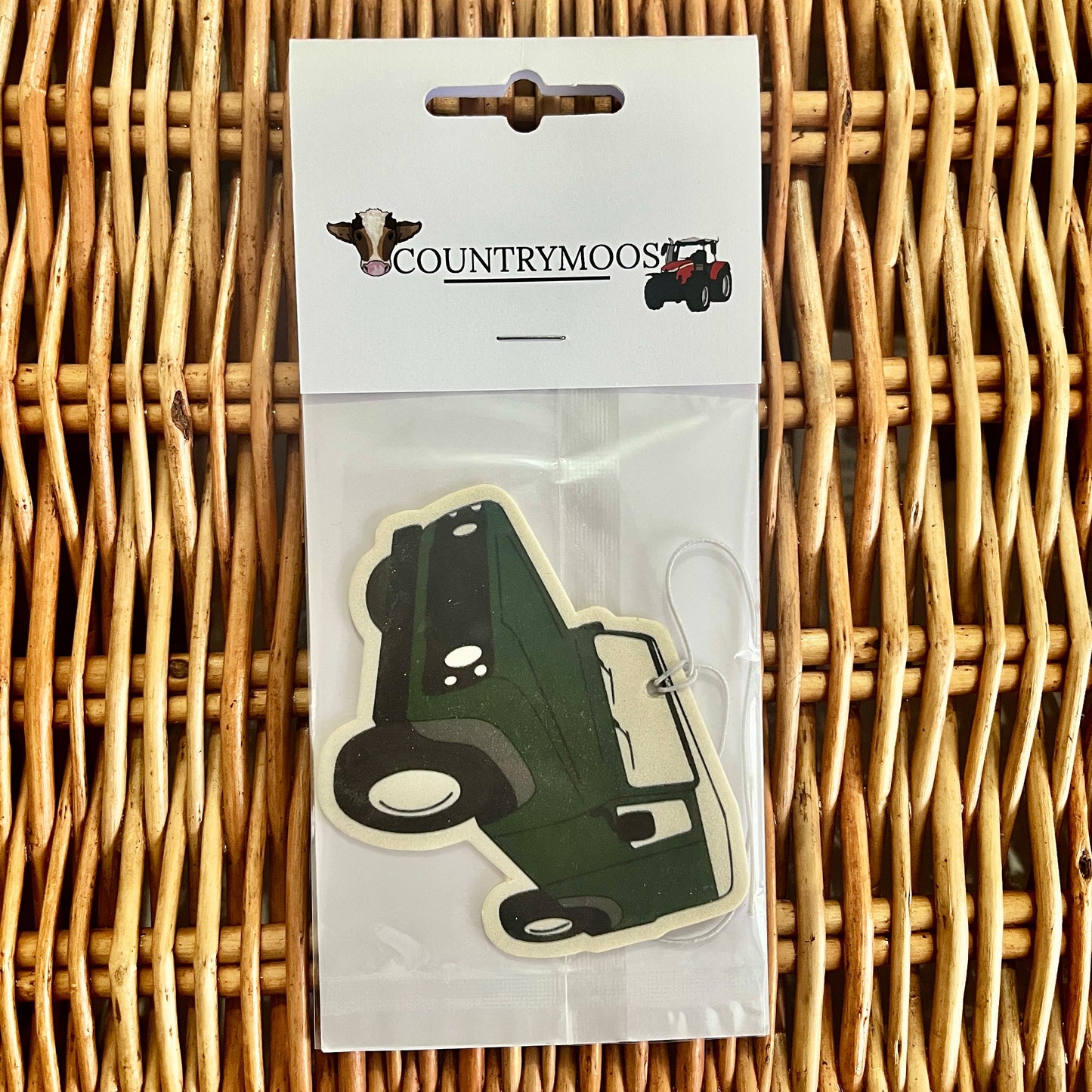 Green Land Rover shaped air freshener in clear packaging on a wicker surface with 'Countrymoos' branding.