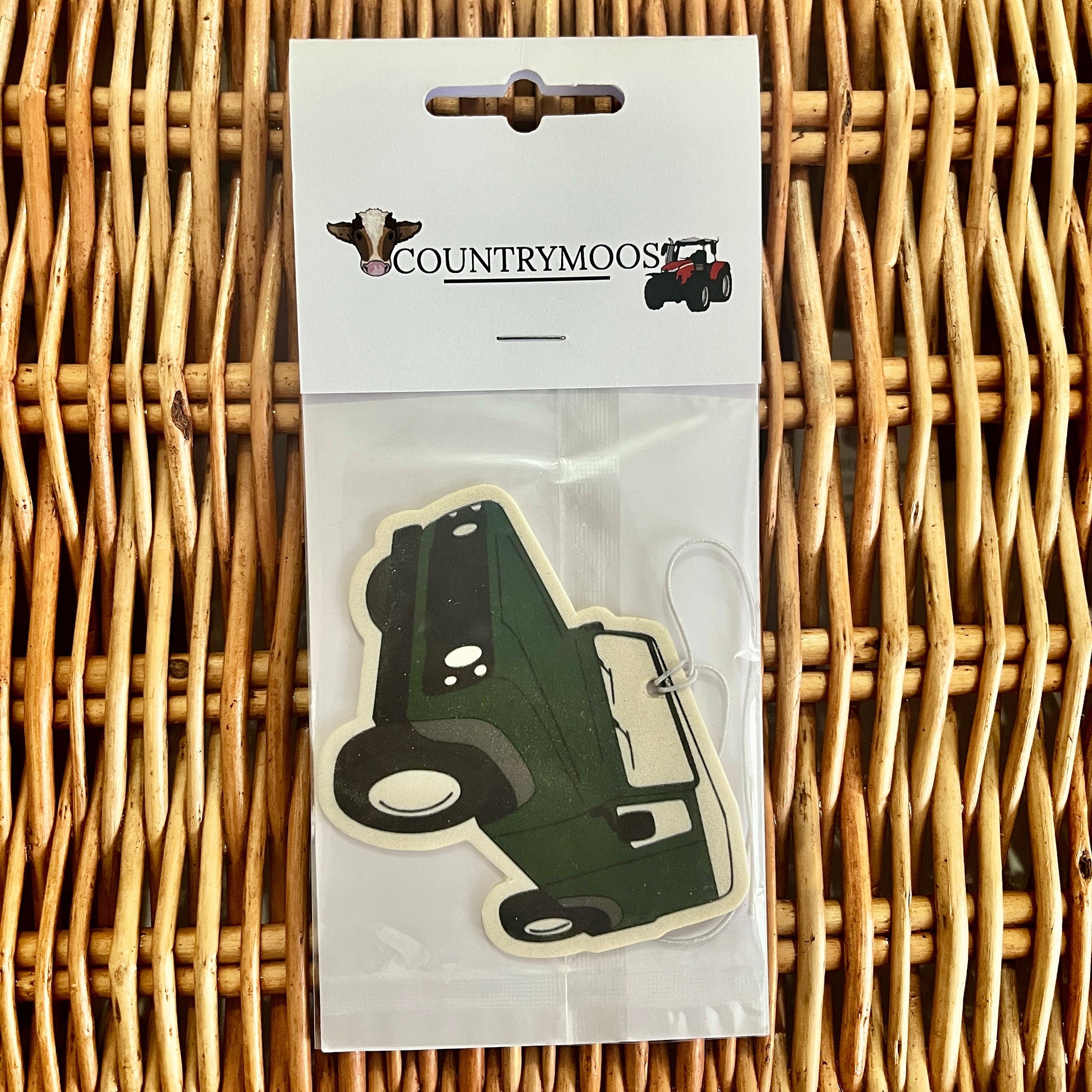 Green Land Rover shaped air freshener in clear packaging on a wicker surface with 'Countrymoos' branding.