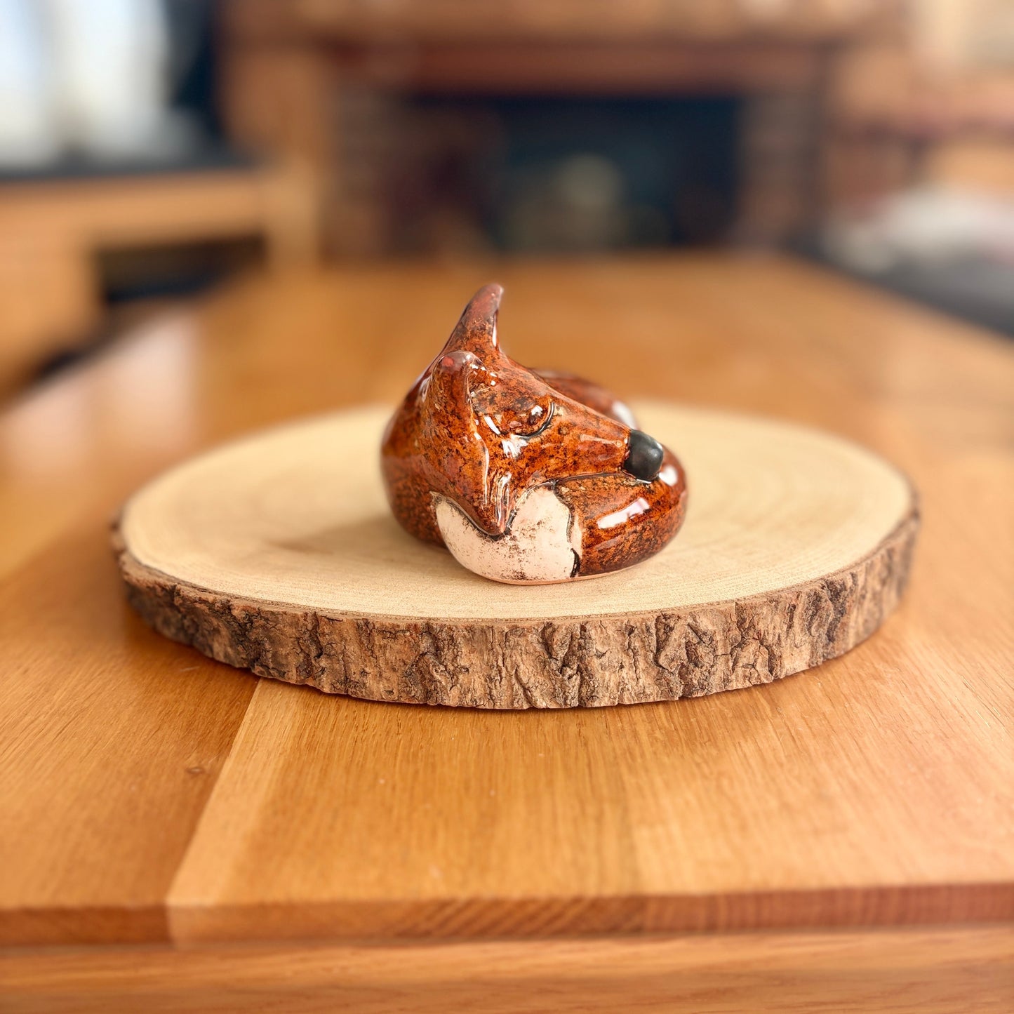 Sleeping fox figurine on a wooden board with a blurred background