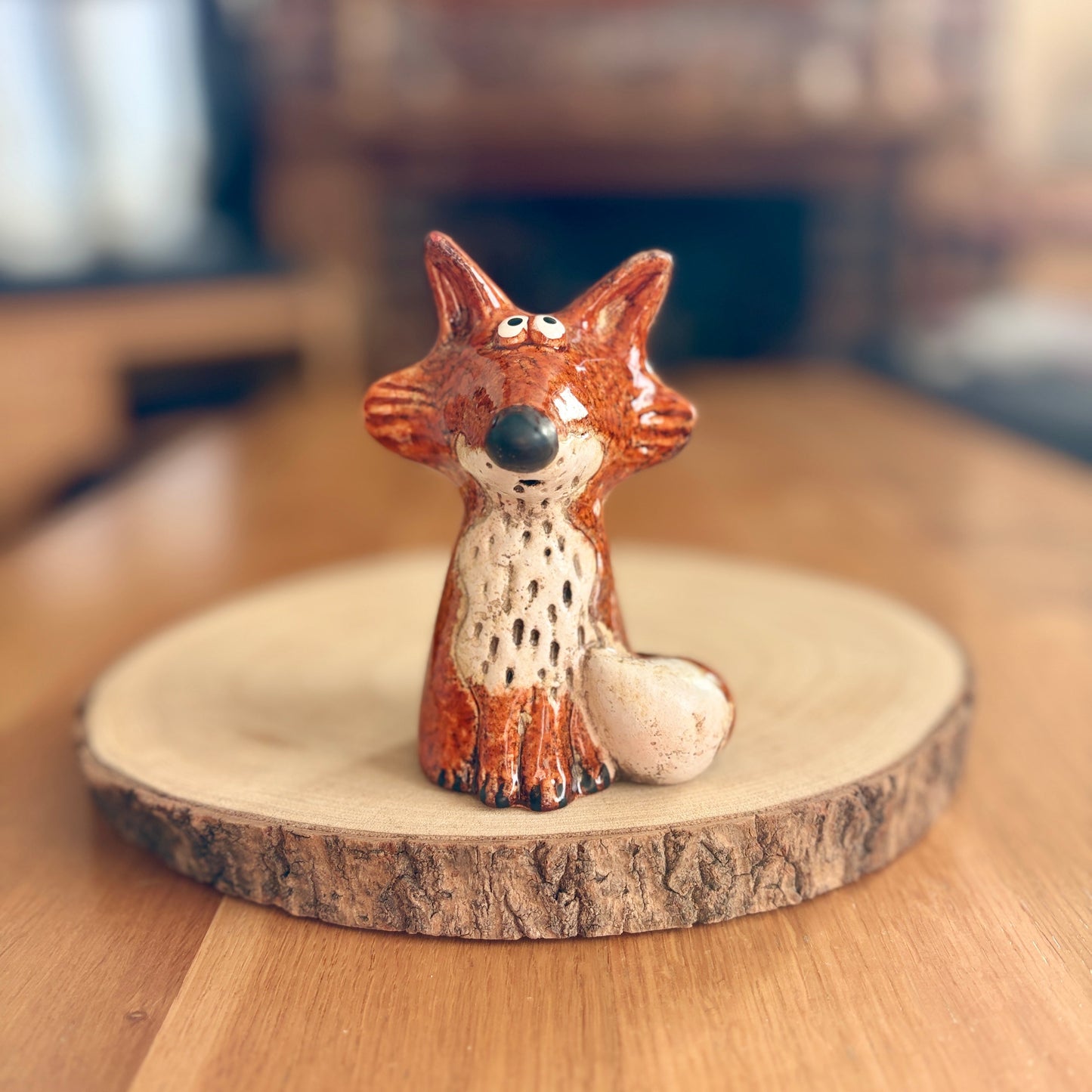 Ceramic fox figurine on a wooden base with a blurred background