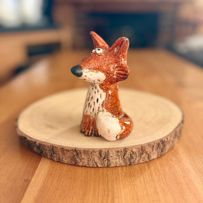 Ceramic fox figurine on a wooden stand with a blurred background