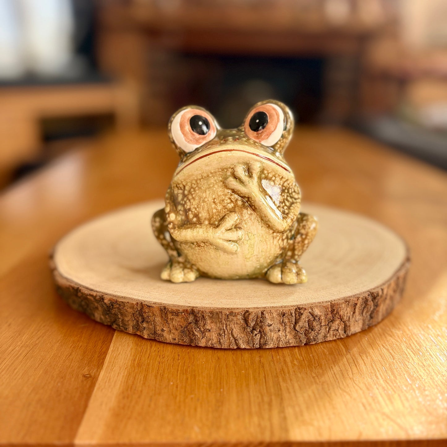 Frog figurine on a wooden base on a wooden surface