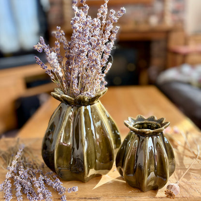 Two green poppy seed ceramic vases with dried lavender on a wooden surface.